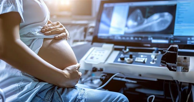 pregnant-woman-sits-front-monitor-with-words-baby-it